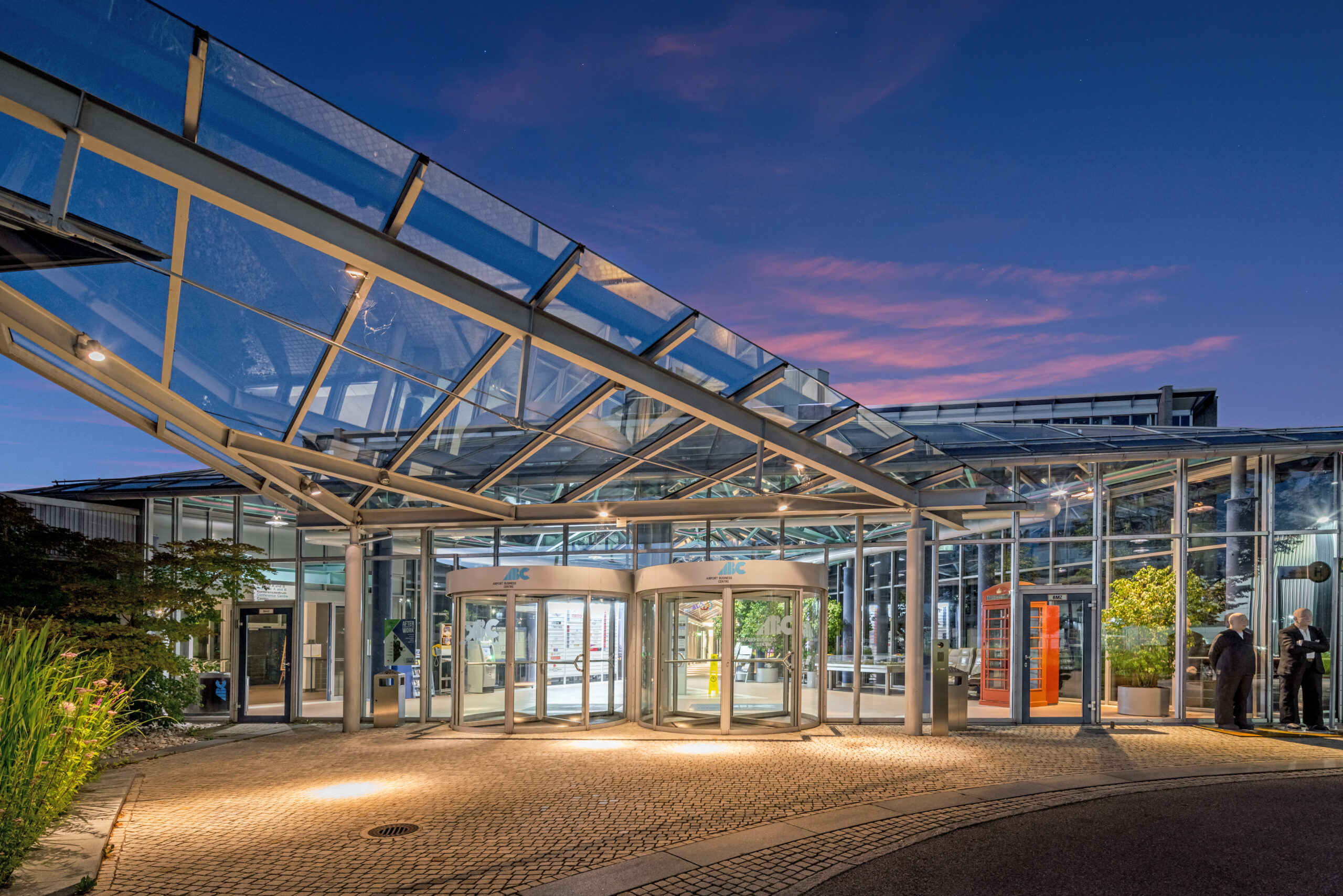 Glasüberdachter Eingang des Airport Business Centre in der Abenddämmerung